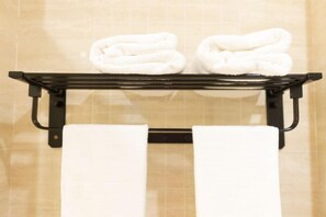 A bathroom with a black towel rack holding two folded white towels and two rolled white towels. - Kunshan Lushan Resort (Kunshan)