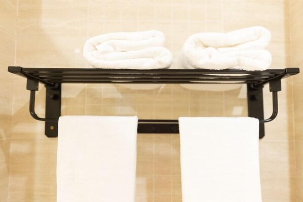 A bathroom with a black towel rack holding two folded white towels and two rolled white towels. - Kunshan Lushan Resort (Kunshan)