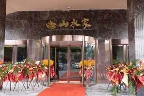 A hotel entrance with a curved facade, a red carpet, and floral arrangements. - Kunshan Lushan Resort (Kunshan)