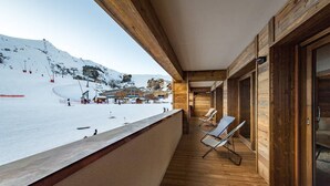 Un balcon en bois donnant sur une piste de ski enneigée.