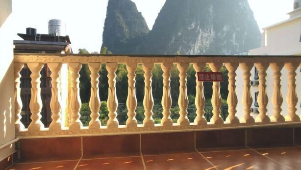 Un balcon agrémenté d’une balustrade décorative, doté d’un sol carrelé et offrant une vue sur une montagne.