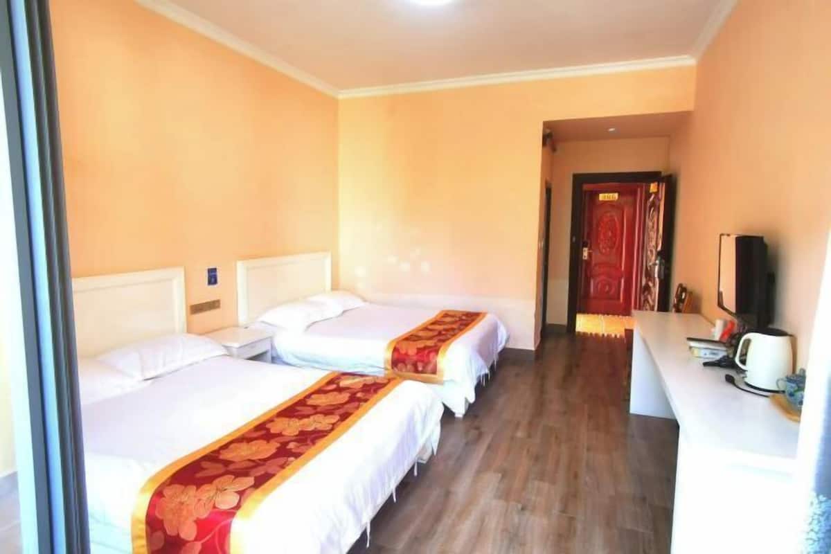 A hotel room with two beds, a desk, and a red door.