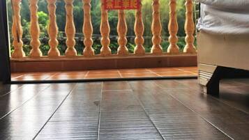 A room with a balcony, a tiled floor, and a sign in a foreign language.