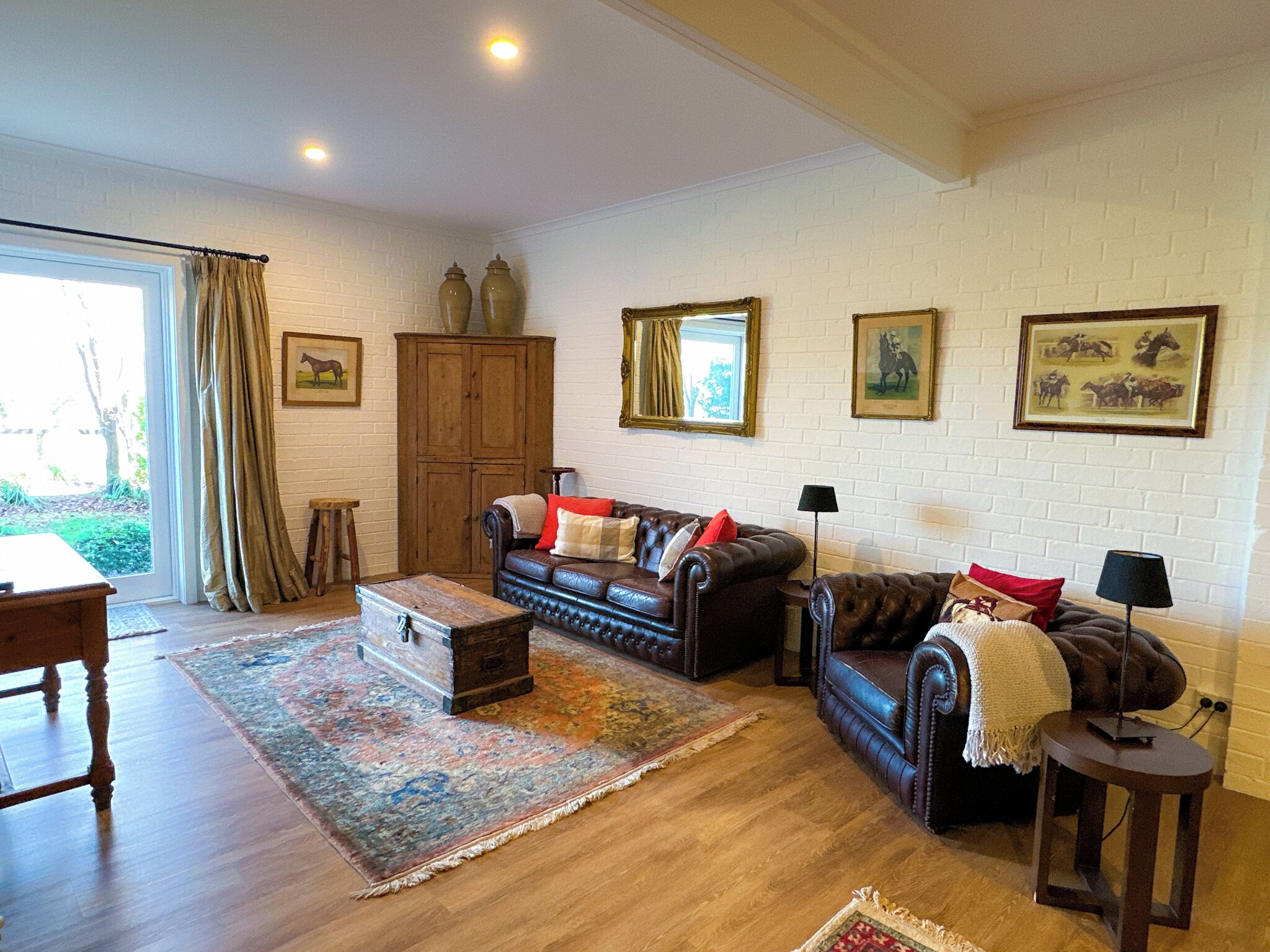 A living room with a brown leather sofa, a wooden cabinet, and a patterned rug.