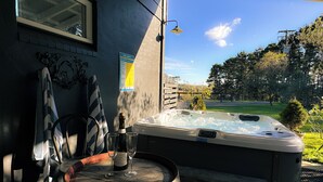 A hot tub with a view of a green landscape, a wooden barrel, and a bottle of wine on a table. - The Grange Berrima - The Ultimate Rural Retreat. Sleeps up to 13. (Berrima)