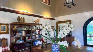 A library with bookshelves, a wooden bench, and a vase with white flowers. - The Grange Berrima - The Ultimate Rural Retreat. Sleeps up to 13. (Berrima)