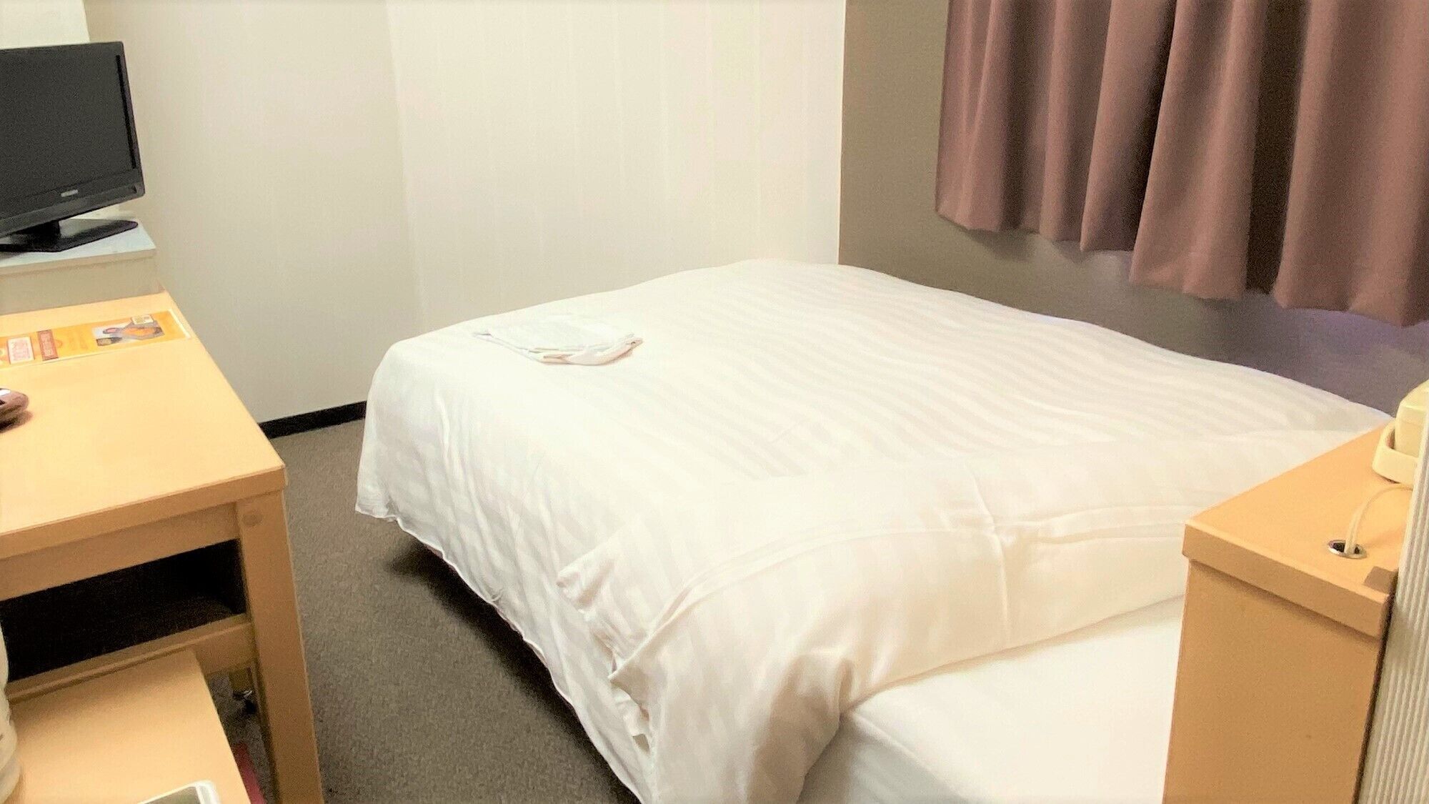 Ein Hotelzimmer mit Bett, Schreibtisch mit Computer und Telefon.