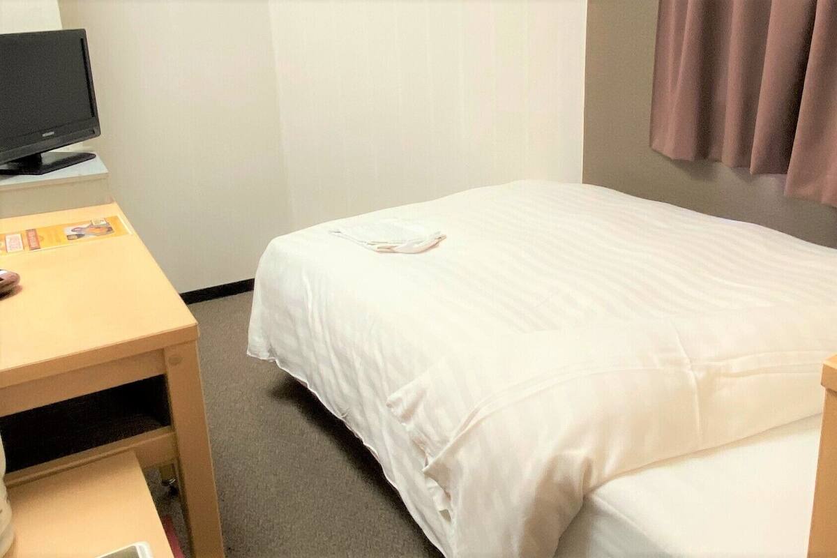 Une chambre d’hôtel avec un lit, un bureau équipé d’un ordinateur et un téléphone.