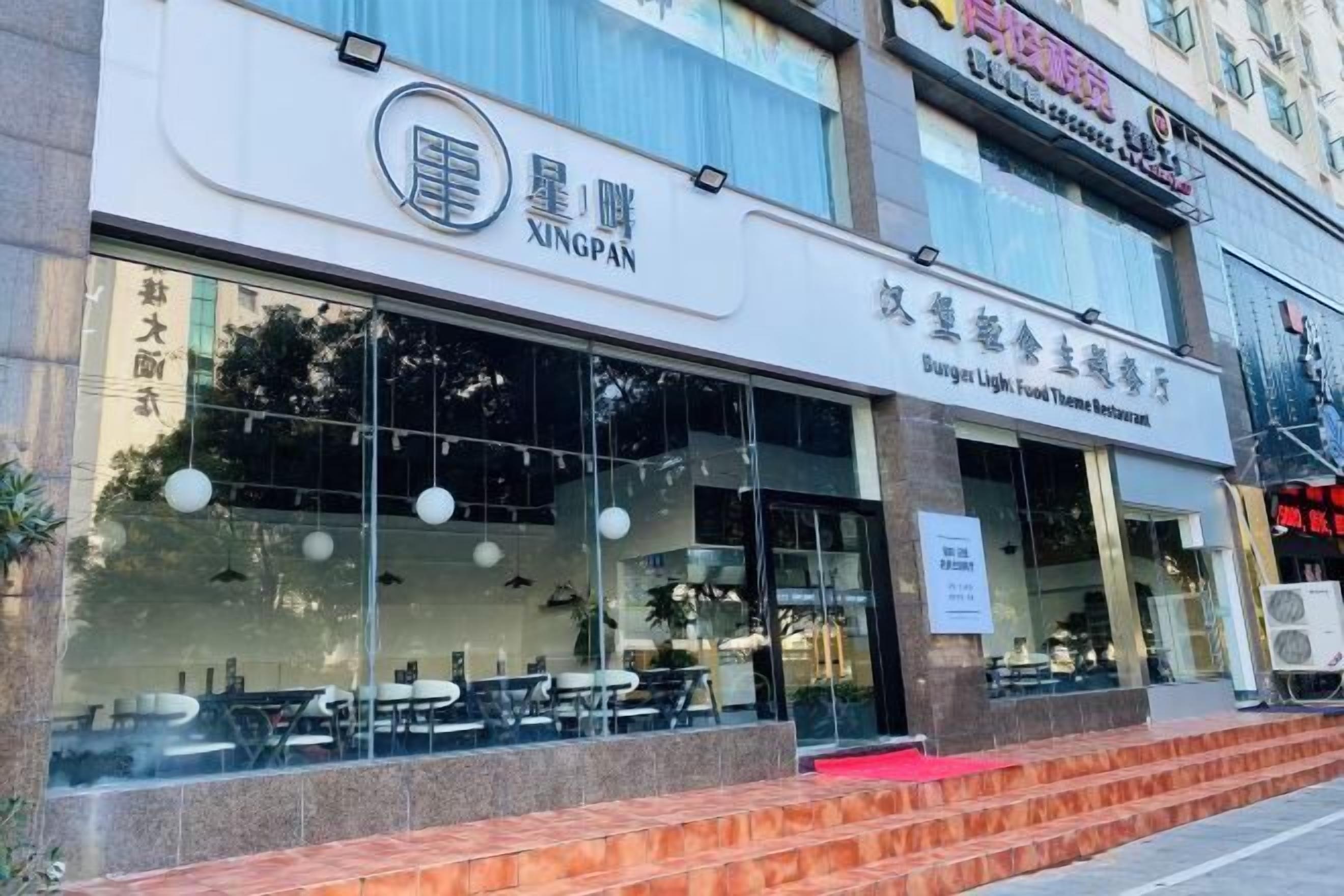 A restaurant with a modern glass facade and outdoor seating visible through the windows.