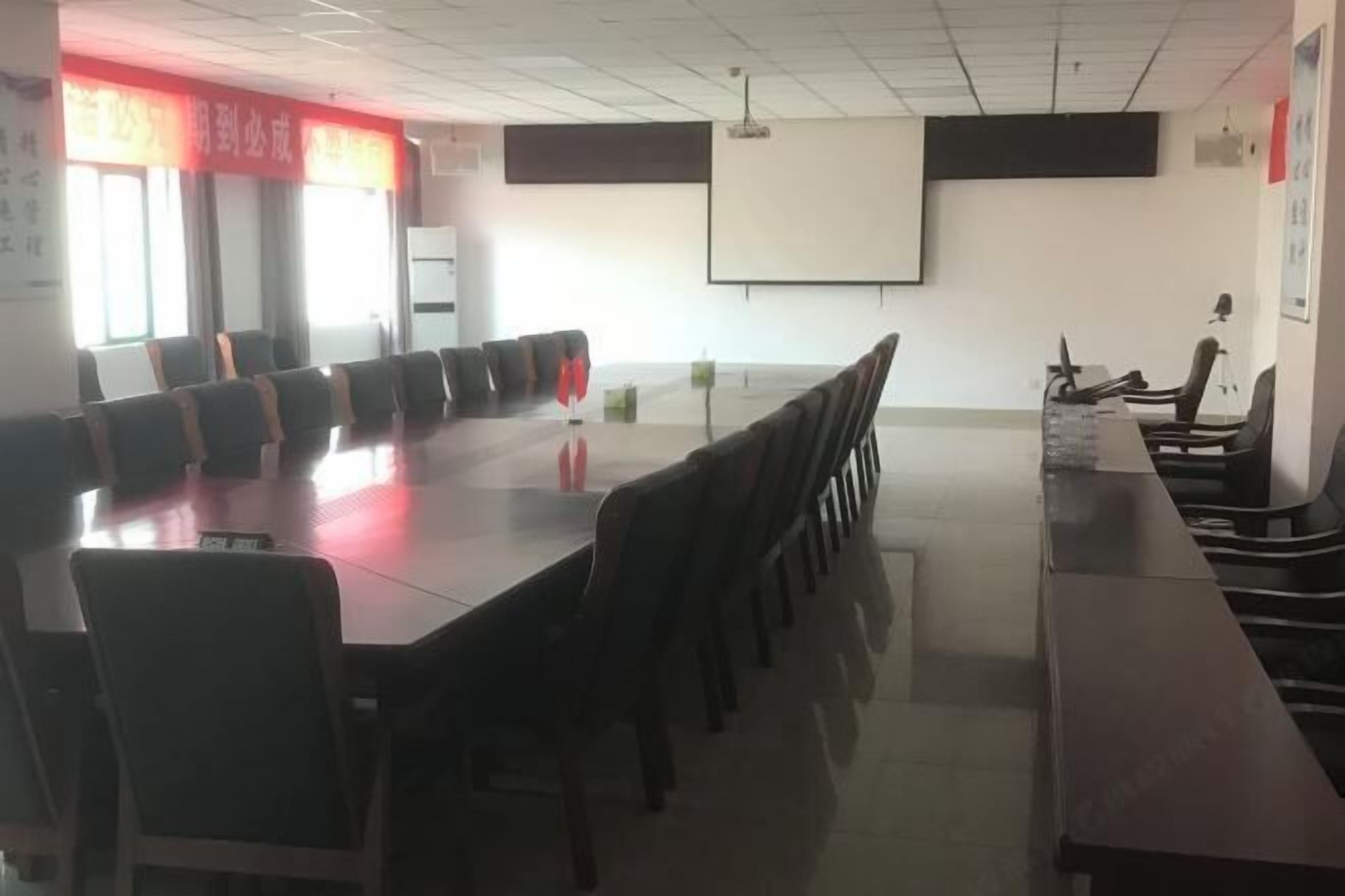 A conference room with a long table and chairs, a projector screen, and a whiteboard.