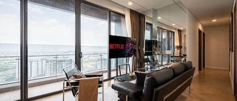 Una sala de estar moderna con un televisor grande, sofá de cuero y vista a la ciudad.