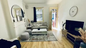 A living room with a sofa, coffee table, TV, and a decorative rug. - Charming, quiet 2.5 bedroom Victorian terrace in the heart of Surry Hills  (Surry Hills)