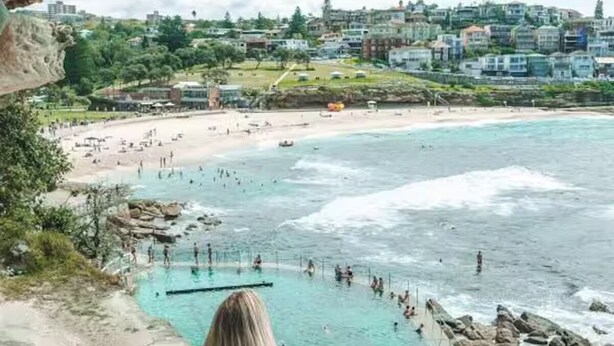 A coastal view with a rocky shoreline, a beach, and a pool area with people swimming and sunbathing. - Charming, quiet 2.5 bedroom Victorian terrace in the heart of Surry Hills  (Surry Hills)