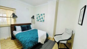 A bedroom with a bed, a chair, a window, and a wall with a picture. - Charming, quiet 2.5 bedroom Victorian terrace in the heart of Surry Hills  (Surry Hills)