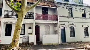 A row of Victorian-style buildings with balconies, a tree in the foreground, and a clear sky. - Charming, quiet 2.5 bedroom Victorian terrace in the heart of Surry Hills  (Surry Hills)