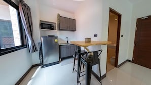 A compact kitchen with a refrigerator, microwave, and wooden table.