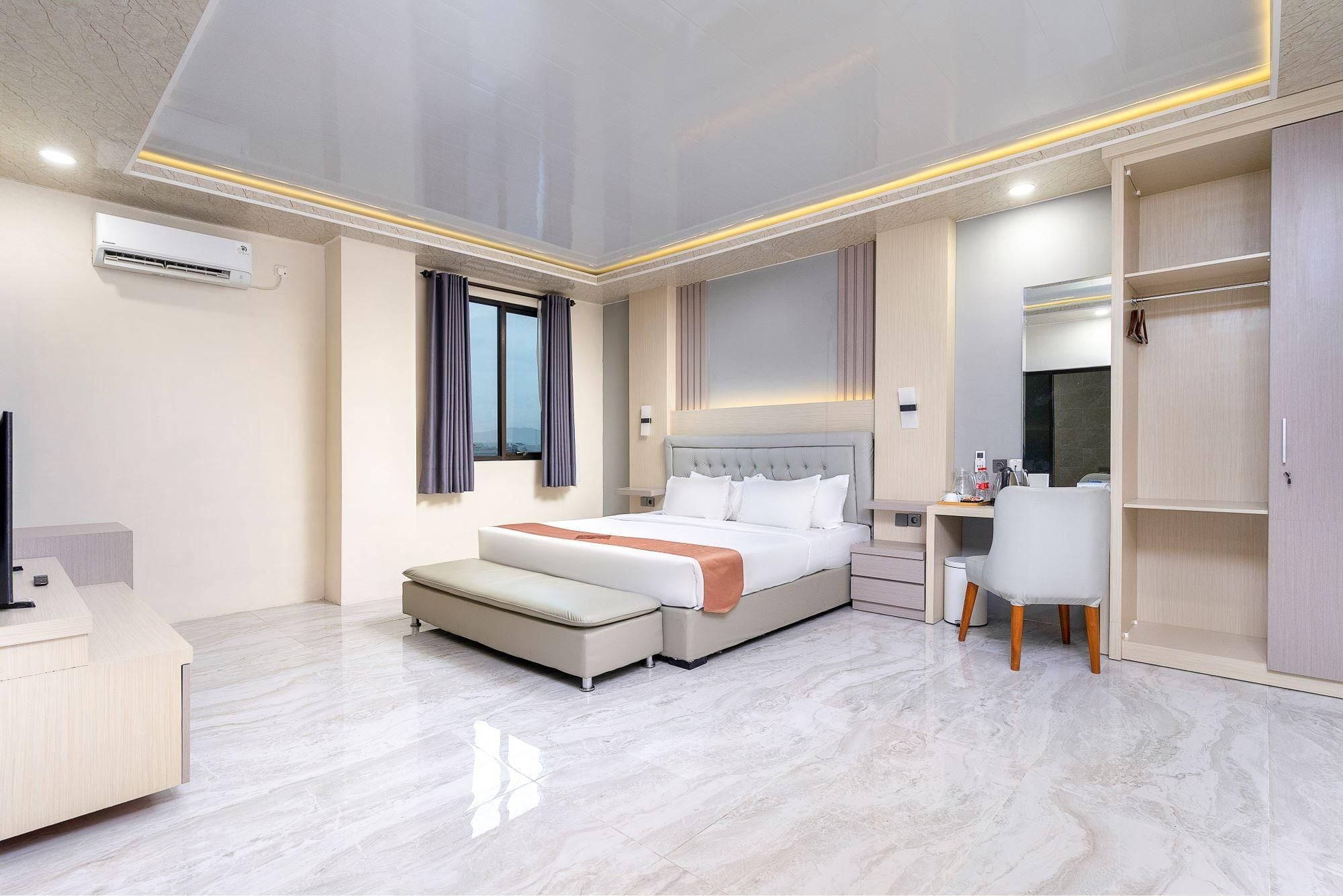 A modern hotel room with a large bed, a desk, and a wardrobe.