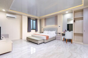 A modern hotel room with a large bed, a desk, and a wardrobe. - Grand Valonia (Sumbersari)