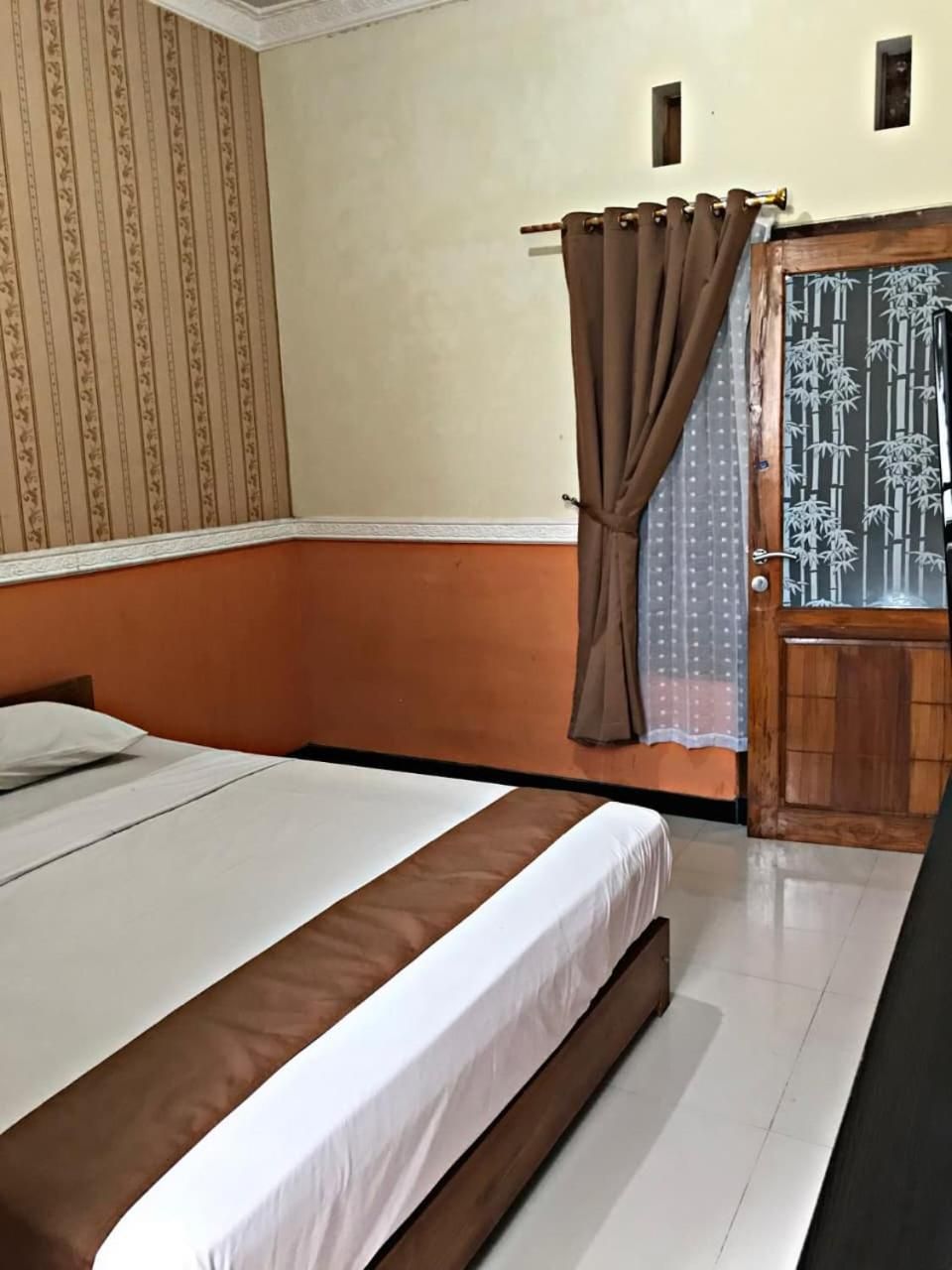A bedroom with a bed, curtains, a door with a bamboo pattern, and a wall with a striped pattern.