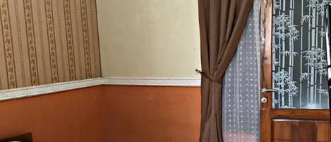 A bedroom with a bed, curtains, a door with a bamboo pattern, and a wall with a striped pattern.
