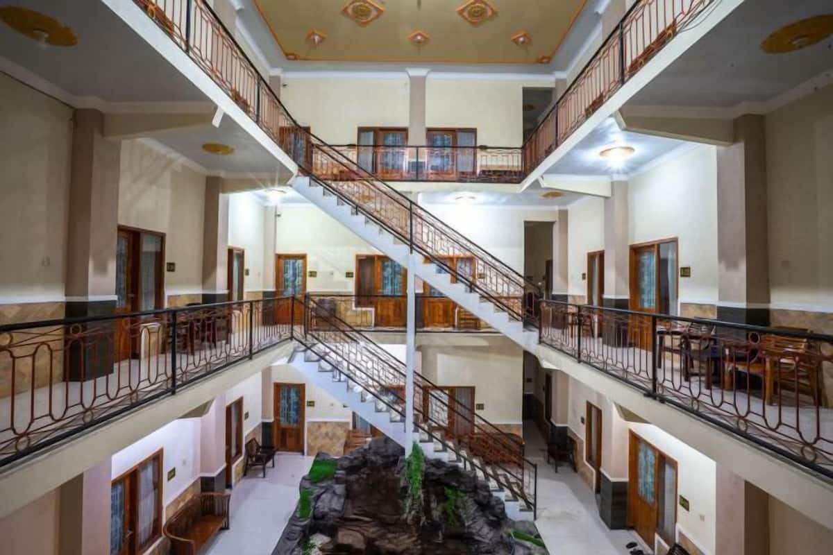Un intérieur d’hôtel à plusieurs niveaux, doté d’un escalier central, de balcons et d’un élément décoratif en roche.