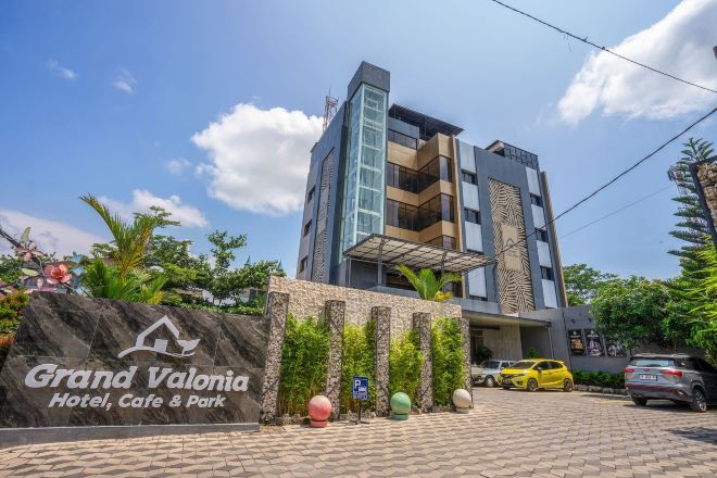 A modern hotel with a sign reading 'Grand Valonia Hotel, Cafe & Park'.