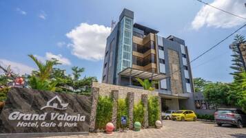 A modern hotel with a sign reading 'Grand Valonia Hotel, Cafe & Park'.