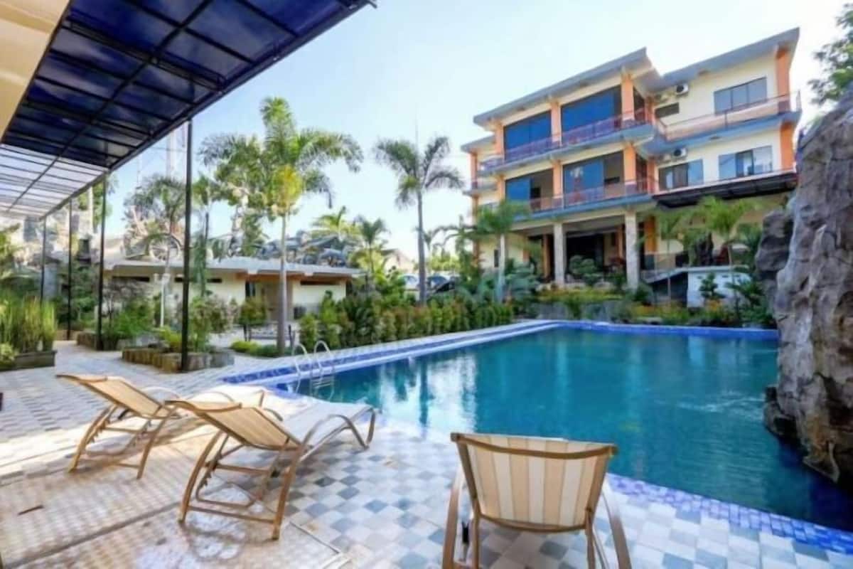 Un hôtel doté d’une piscine, de chaises longues et d’un patio couvert.