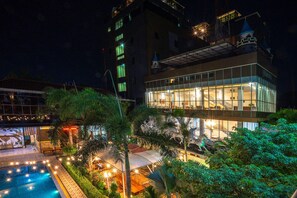 Un hôtel doté d’une piscine, d’un espace extérieur aménagé et d’une façade bien éclairée.