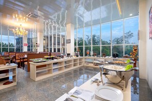 Un comedor amplio con techos altos, ventanas grandes y diversas estaciones de servicio de alimentos.