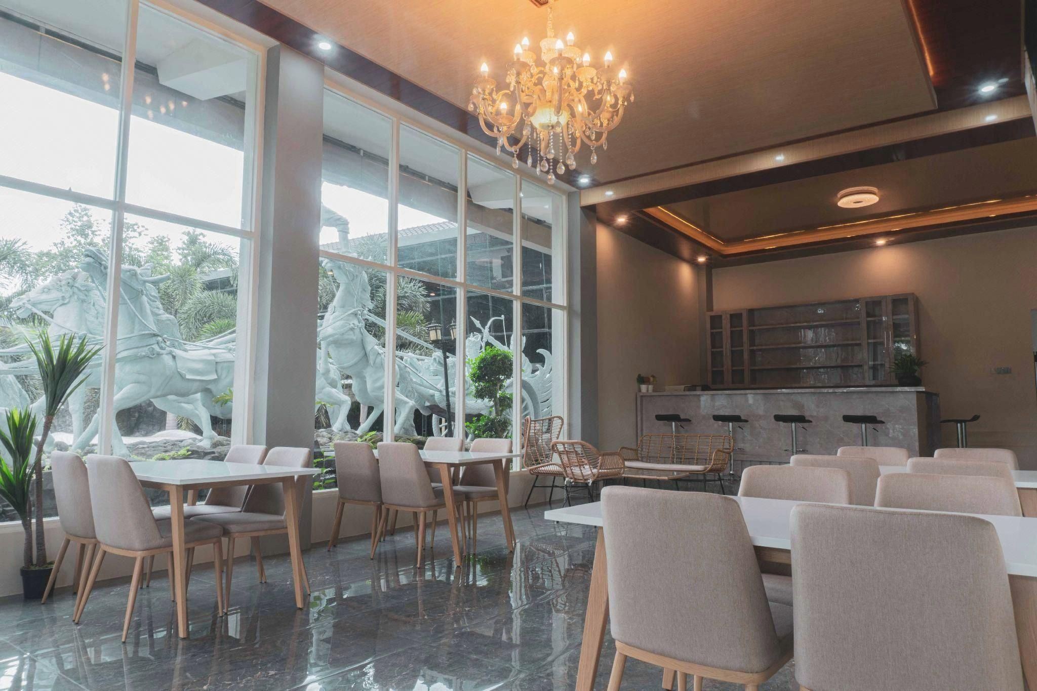 A modern dining area with a chandelier, large windows, and a view of outdoor sculptures.