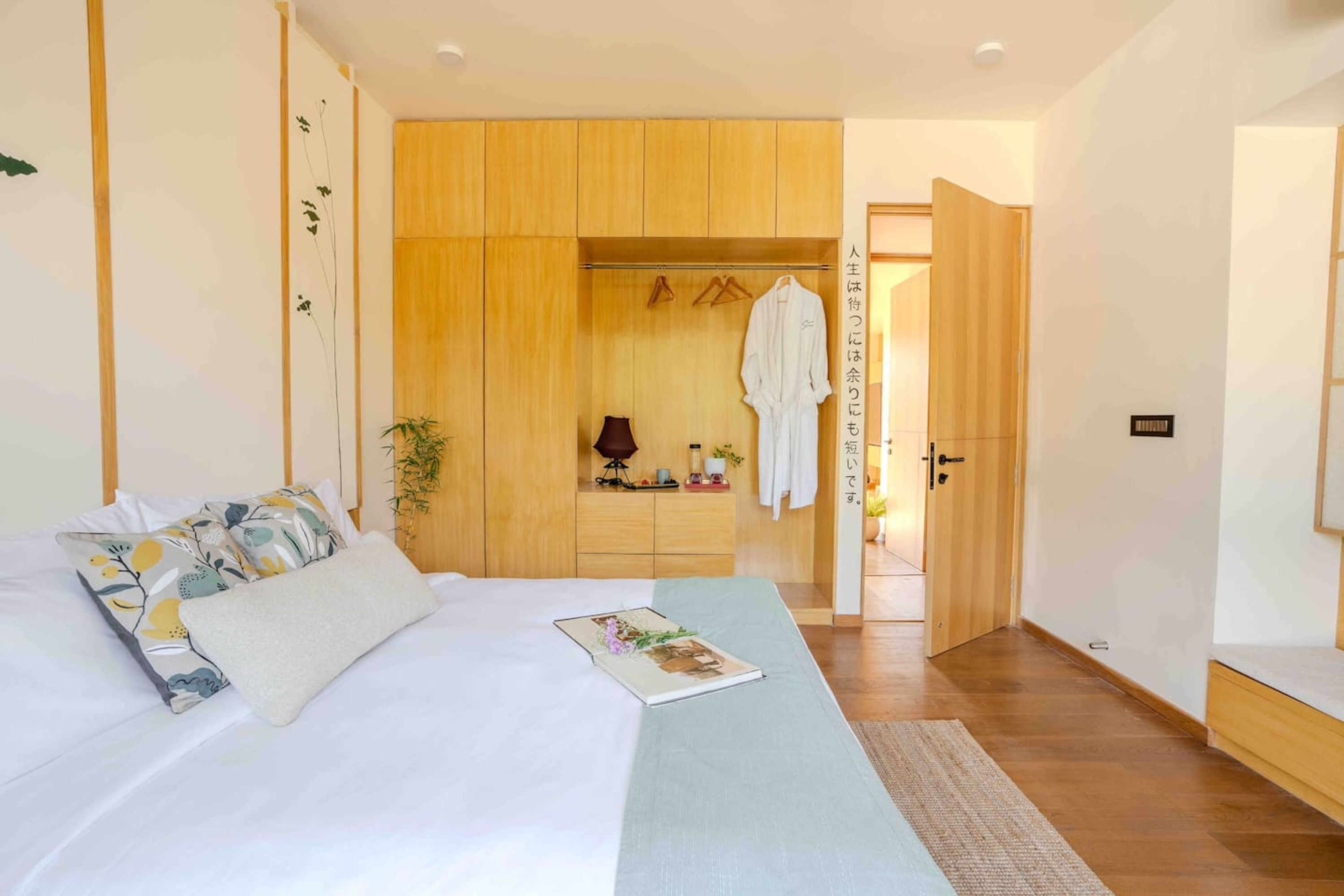 A bedroom with a bed, a bedside table, a hanging robe, and a wooden wardrobe.