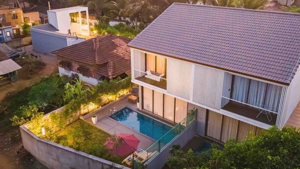 A modern two-story house with a swimming pool, surrounded by lush greenery and palm trees. - Villa Samurai - Japanese Villa w Pool North Goa (Siolim)