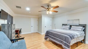 Ein Schlafzimmer mit Bett, Schreibtisch, Stuhl, Deckenventilator und Fernseher.