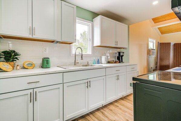 A modern kitchen with white cabinets, a wooden countertop, and a green dishwasher.
