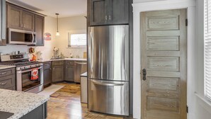 A modern kitchen with stainless steel appliances, dark wooden cabinets, and a wooden door.