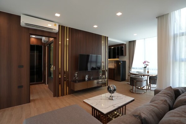 A modern living room with a TV, sofa, and a dining area with a table and chairs.