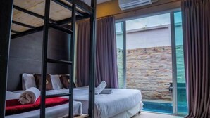 A room with bunk beds, a large window with curtains, and a stone wall outside. - Berich Poolvilla Pattaya (Pattaya)