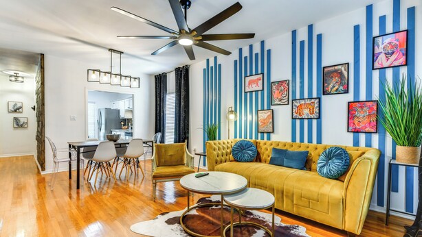 A modern living room with a yellow sofa, round coffee table, and a ceiling fan.