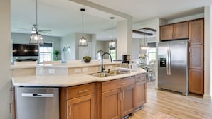 Una cocina moderna con armarios de madera, electrodomésticos de acero inoxidable e iluminación colgante.