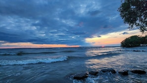 Paisaje costero con olas, rocas y un atardecer.
