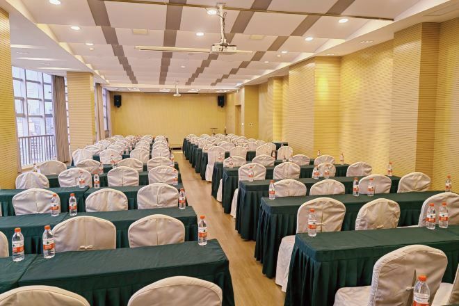 A conference room with rows of tables and chairs, equipped with water bottles.