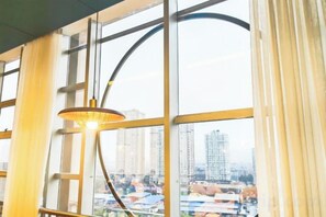 Una habitación con ventanas amplias, una lámpara colgante y vistas a un paisaje urbano.