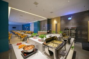 A buffet setup with various food items and a seating area with tables and chairs. - Meitian Holiday Hotel (Shaanxi University of Technology) (Hanzhong)