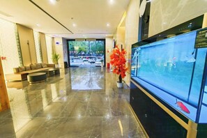 A hotel lobby with a reception desk, seating area, and a large aquarium. - Meitian Holiday Hotel (Shaanxi University of Technology) (Hanzhong)