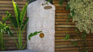 Un mur de pierre agrémenté d’une douche intégrée, d’une piscine et d’une végétation luxuriante.