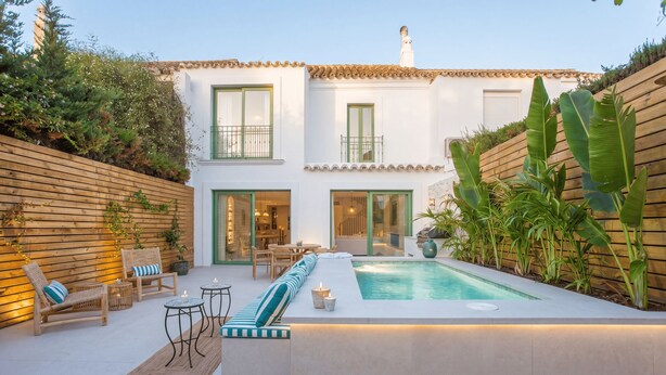 Une maison moderne dotée d’une piscine, d’un espace salon extérieur et d’une clôture en bois.