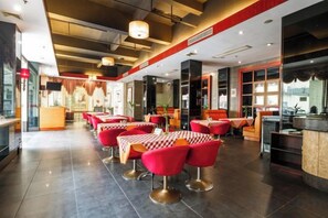Un restaurant avec des chaises et des tables rouges, un bar et un comptoir.