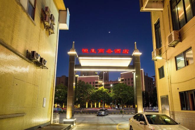 A building entrance with a prominent sign, a parking area, and a clear sky.