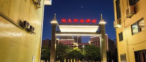 A building entrance with a prominent sign, a parking area, and a clear sky.